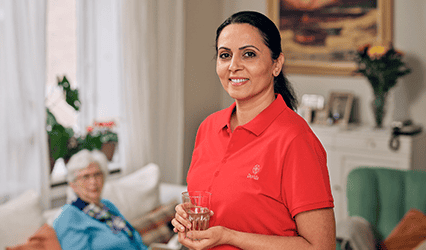 A Dovida Caregiver brings a female client a glass of water