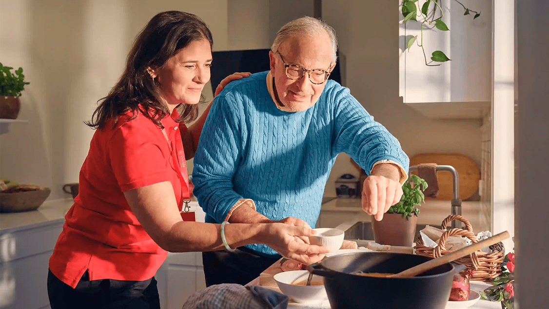 A carer helps a client make dinner